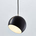 Black spherical pendant light with warm white interior glow and metallic accent, suspended against neutral background.
