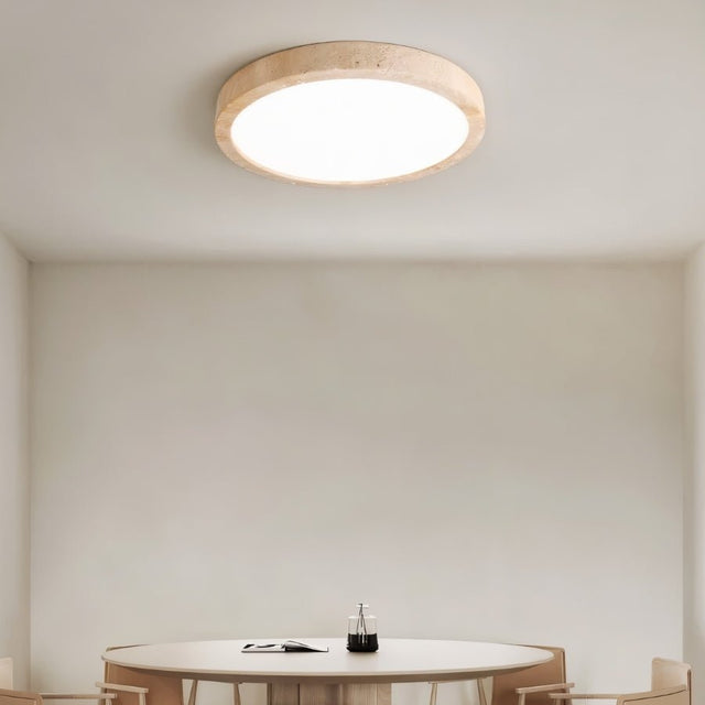 "A minimalist, natural travertine ceiling light illuminates a modern dining room with soft, uniform light."