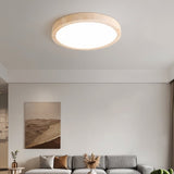 "A minimalist, natural travertine ceiling light illuminates a modern living room with artwork and soft, uniform light."
