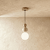 Three stacked spheres pendant light in clear glass with brushed metal hardware on white studio background.