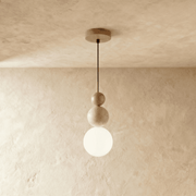 Three stacked spheres pendant light in clear glass with brushed metal hardware on white studio background.
