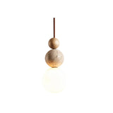 "Sculptural pendant light with stacked travertine, wood, and metal elements, featuring a frosted glass diffuser, isolated on a white background."