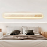"Minimalist travertine wall light installed above a bed, creating a warm and inviting atmosphere"