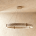 Cork-textured circular LED pendant light with warm glow suspended above dining table in modern interior.
