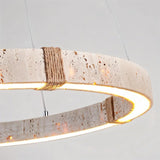 "Close-up of a circular travertine chandelier with an integrated LED strip and hemp rope detailing, showcasing its raw, textured aesthetic."