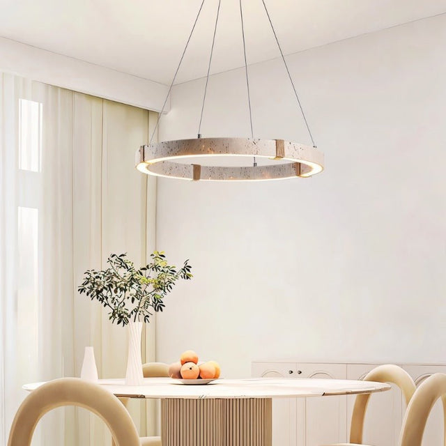 "Minimalist circular chandelier made of travertine, iron, and acrylic hanging above a dining table in a bright, modern dining room."