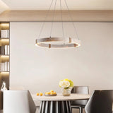 "Circular chandelier made of travertine, iron, and acrylic hanging above a dining table with chairs, creating a modern and elegant ambiance."