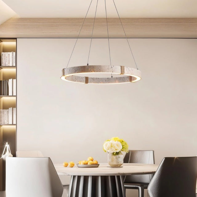 "Circular chandelier made of travertine, iron, and acrylic hanging above a dining table with chairs, creating a modern and elegant ambiance."