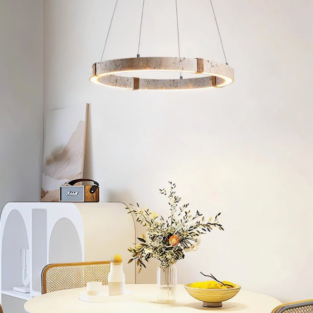 "Modern circular chandelier made of travertine, iron, and acrylic hanging above a round dining table with cane chairs."