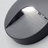 "Close-up detail of a sleek, round step light with a clear acrylic diffuser, showcasing the grooved faceplate designed to reduce glare and efficiently direct light in indoor and outdoor spaces."