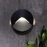 "A sleek, round, minimalist wall light with a clear acrylic diffuser, mounted on a textured wall, providing a soft, focused downward glow."