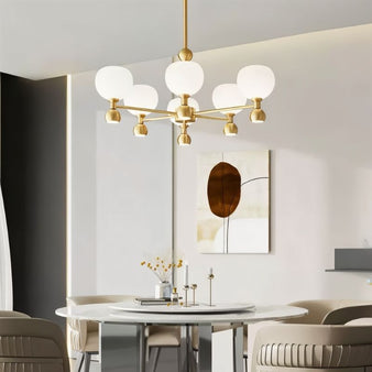 "A 6-light gold sputnik chandelier with frosted glass globes, hanging above a dining table in a modern dining room."