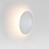 Close-up of the Rochi Wall Lamp in white aluminum, showcasing its round, minimalistic design and soft ambient lighting.