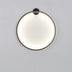 Black metal circular wall lamp with illuminated white frosted glass diffuser mounted on gray wall.