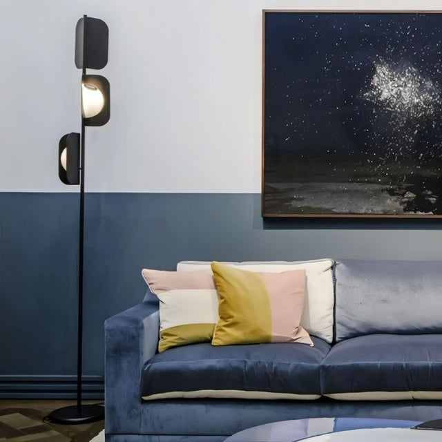 "A black floor lamp in a modern living room setting with a blue sofa."