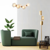 "A gold floor lamp in a modern living room setting with a green sofa."