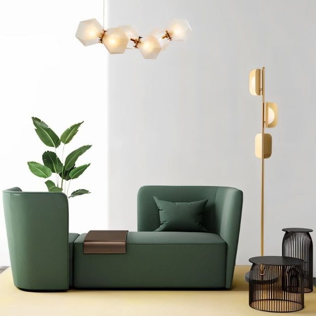 "A gold floor lamp in a modern living room setting with a green sofa."