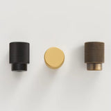 "Knurled brass knobs in three finishes: black, gold, and antique, suitable for modern cabinetry and drawers."