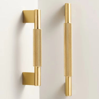 "Pair of gold knurled brass pull bars with clean edges, blending industrial design and functionality for modern spaces."