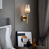 "Modern wall lamp with copper base, gold finish, and textured glass shade providing a soft glow in a contemporary bedroom setting."
