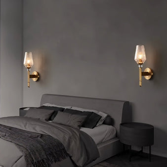 "Pair of modern wall lamps with copper base, luxurious gold finish, and textured glass shade providing a soft, elegant glow in a contemporary bedroom."