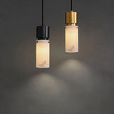 "Modern pendant lights with cylindrical alabaster shades and metallic accents, hanging against a dark background."