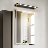 "A modern black and gold wall lamp with an adjustable cylindrical light bar above a rectangular bathroom mirror."