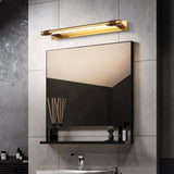 "A modern gold and brown wall lamp with a sleek, adjustable cylindrical light bar mounted above a rectangular mirror in a contemporary bathroom with a minimalist shelf."