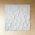 White textured 3D wall panels with organic shapes arranged on a wall behind a cream upholstered sofa in a modern interior set