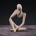 Beige stone figurine of a seated contemplative figure against a dark background.