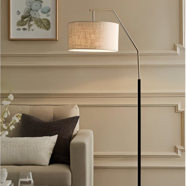 "Iron floor lamp with a black frame and fabric drum shade, providing soft, diffused lighting in a cozy, modern living room."
