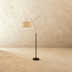 Arc floor lamp with linen drum shade, brushed nickel finish, arching over beige sofa in neutral living room setting.