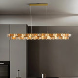 "Iron Salane chandelier with layered amber glass elements hanging above a kitchen with grey cabinets."