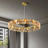 "Round iron Salane chandelier with layered amber glass elements hanging in a living room with large windows."
