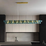 "Iron Salane chandelier with layered blue glass elements hanging above a modern kitchen with grey cabinets."