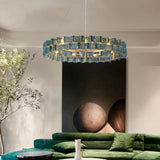 "Iron Salane chandelier with layered blue glass elements hanging above a living room with a green sofa."