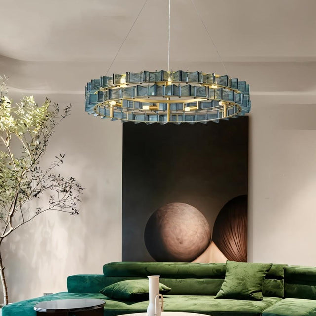 "Iron Salane chandelier with layered blue glass elements hanging above a living room with a green sofa."