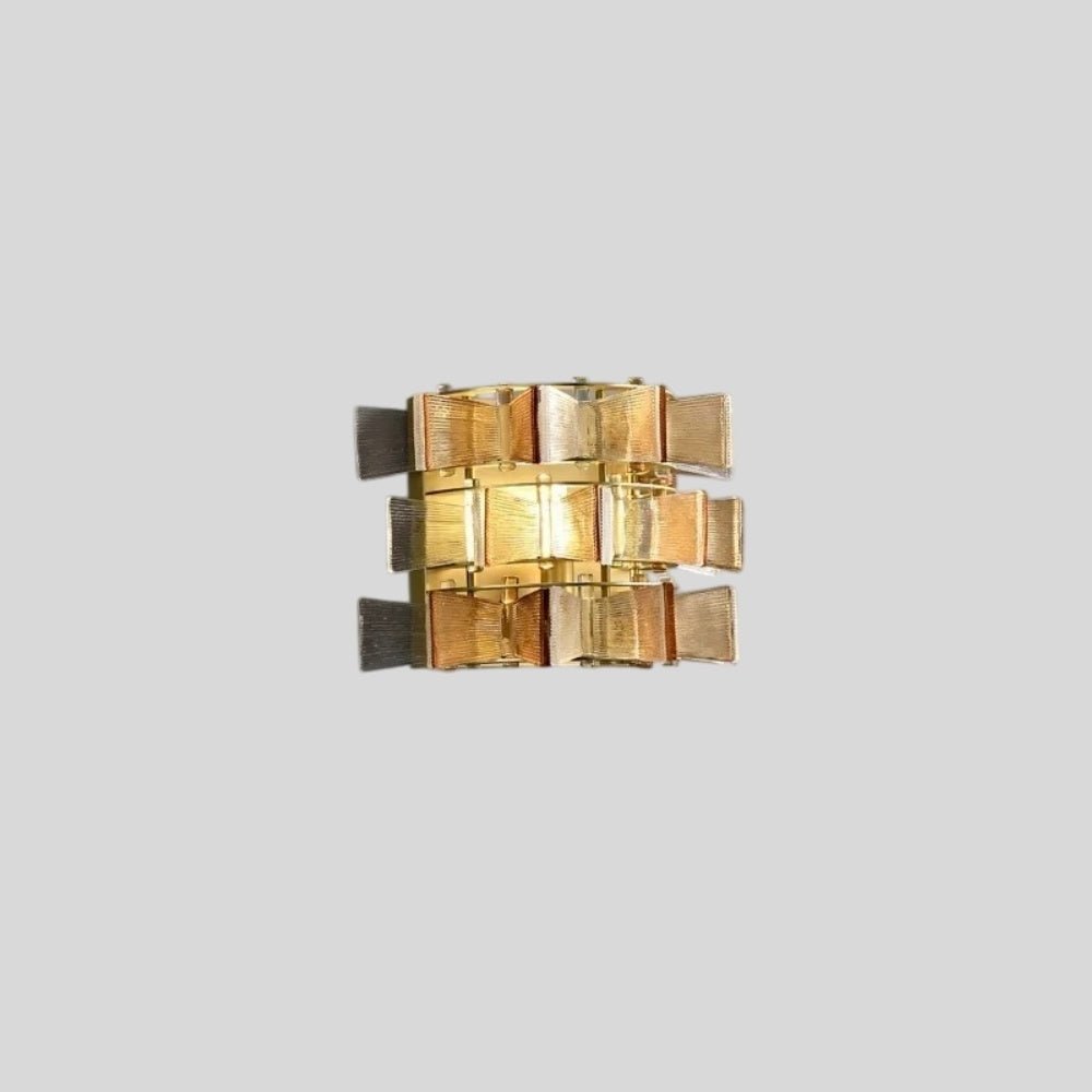 "Isolated iron Salane wall lamp with layered amber glass panels and visible shadows, on a light grey background."