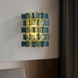 "Iron Salane wall lamp with layered blue glass panels, mounted on a wall in a bedroom."