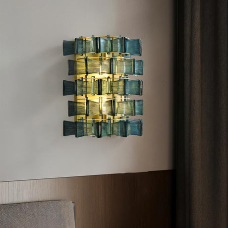 "Iron Salane wall lamp with layered blue glass panels, mounted on a wall in a bedroom."