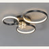 Modern black metal ceiling light with three illuminated rings and a crystal sphere centerpiece on gray background.