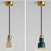 Pendant light with brass canopy, black cord, and alabaster shade in white marble finish against neutral background.