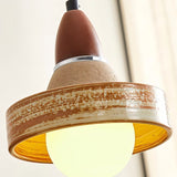 "Close-up of a handcrafted ceramic pendant light shade with a textured surface and a warm, glowing light bulb."
