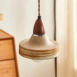 "Handcrafted pendant light featuring a textured ceramic shade and a wooden top, blending rustic and modern design elements."