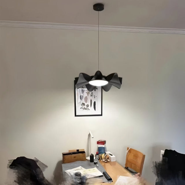 "Sculptural pendant light with a wave-like iron frame and acrylic diffuser illuminating a modern room with a balanced glow."