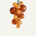 Amber glass globe chandelier with cascading spheres in varying sizes on dark metal chain against white background.