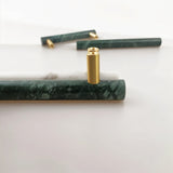 "Arrangement of marble and brass pull bar components, showcasing the cylindrical design and materials."