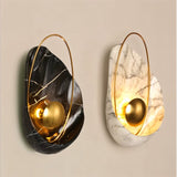 "Pair of modern resin wall lamps with shell shapes, one black and one white, with gold spheres and metal hoops."