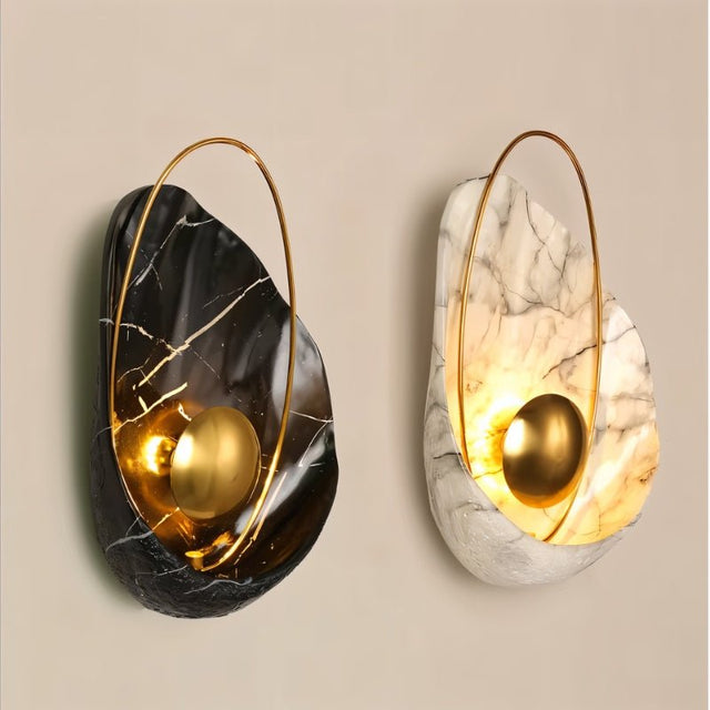 "Pair of modern resin wall lamps with shell shapes, one black and one white, with gold spheres and metal hoops."