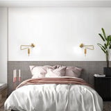 "Pair of gold adjustable arm bedside reading lamps mounted on a bedroom wall."